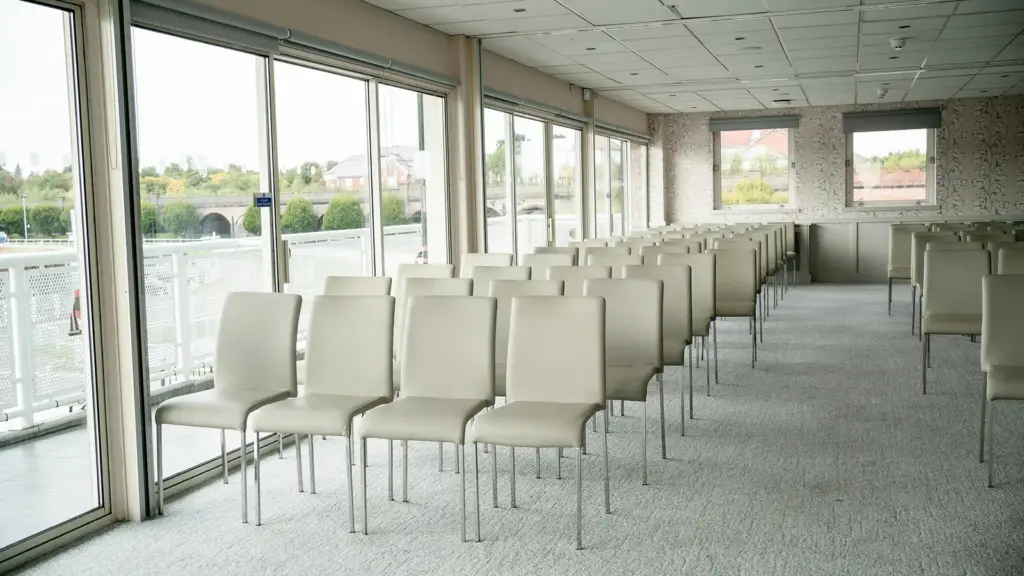 A Leverhulme Stand room with rows of chairs beside floor to ceiling windows onto a balcony