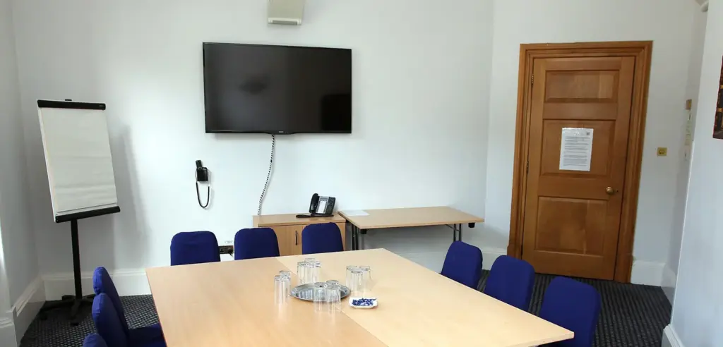 Oscar Wilde Room with a meeting table, wall-mounted screen and flip chart